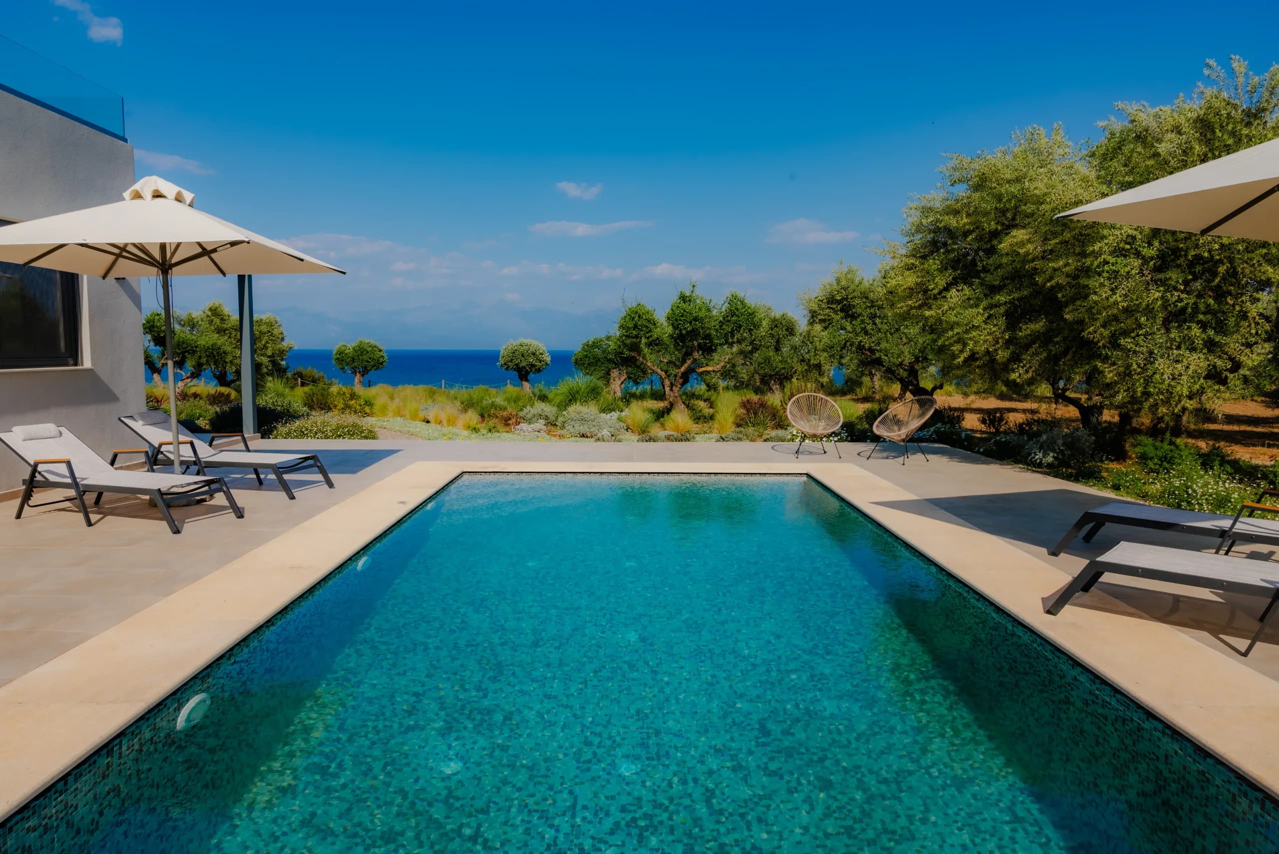 Swimming pool with sunbeds looking out over the sea