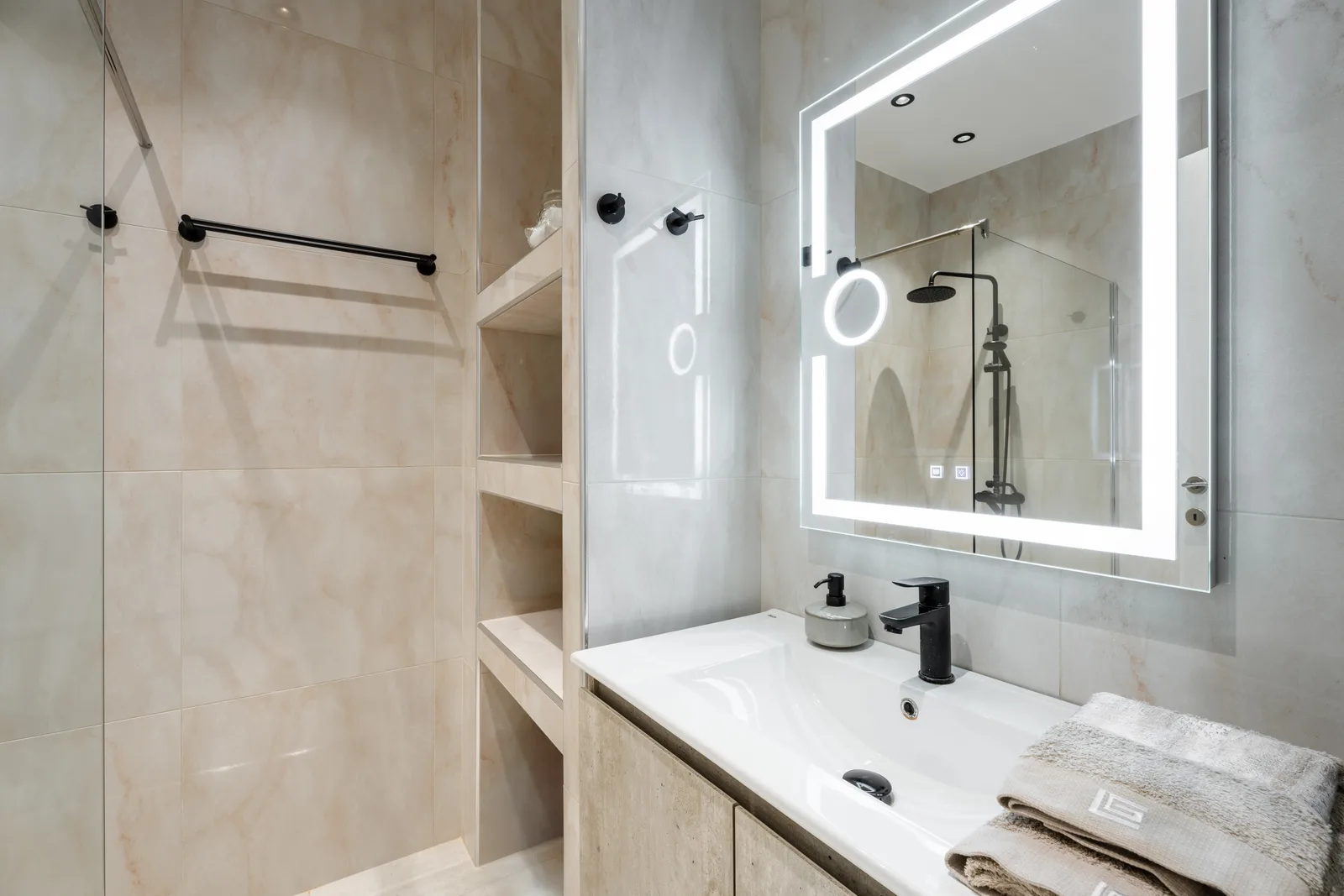 Bathroom with a backlit round mirror, open shelving and a walk in shower