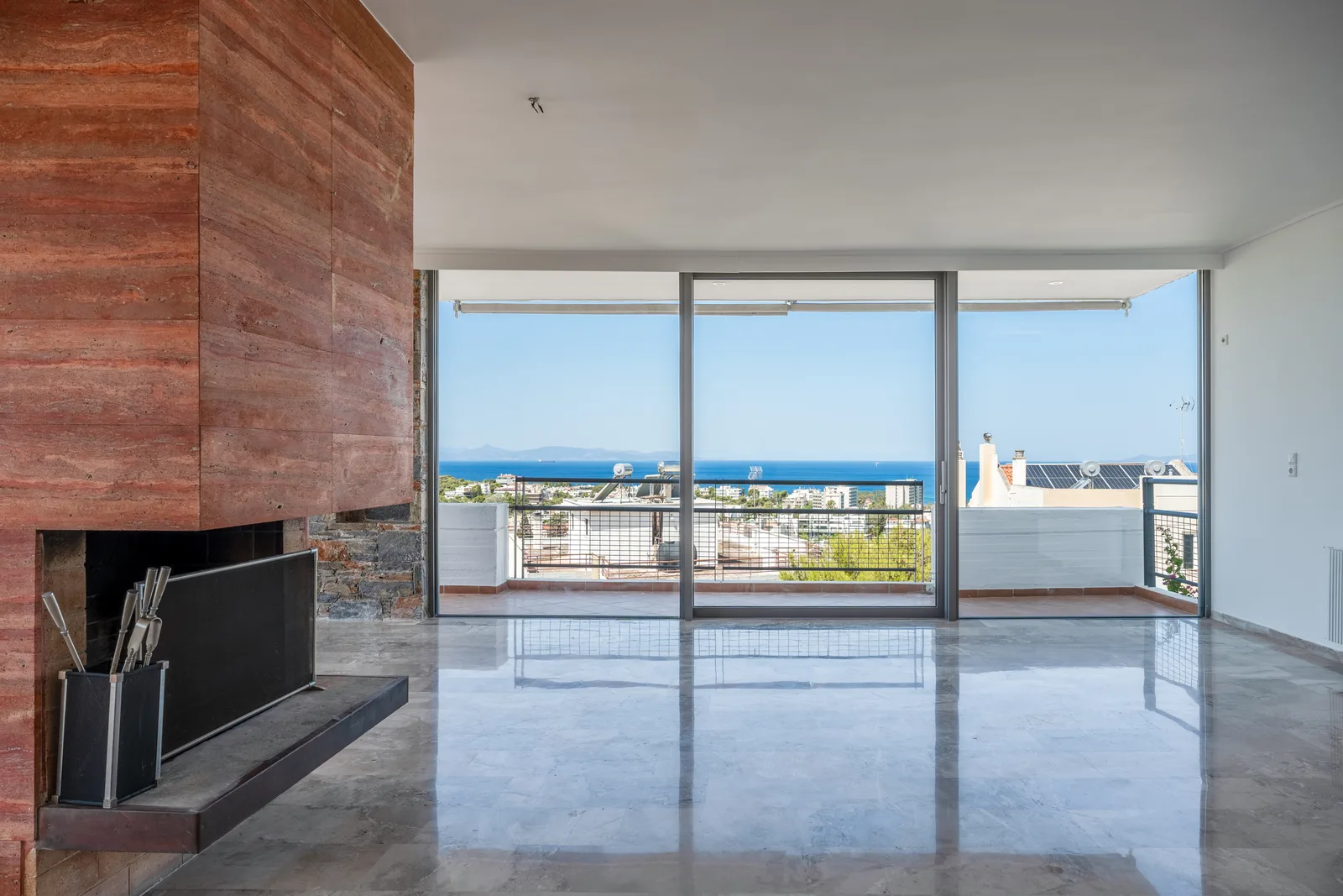 Living room opening onto a balcony with a sea view and a fireplace