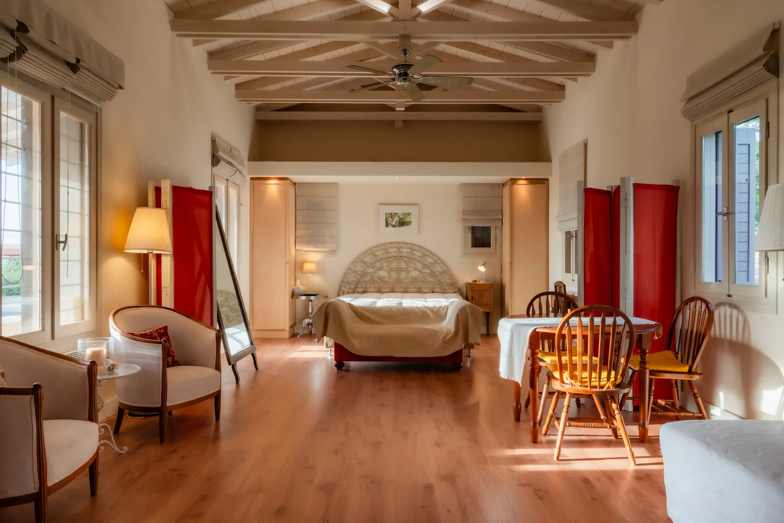Open living and dining room with a wooden ceiling and red drapes
