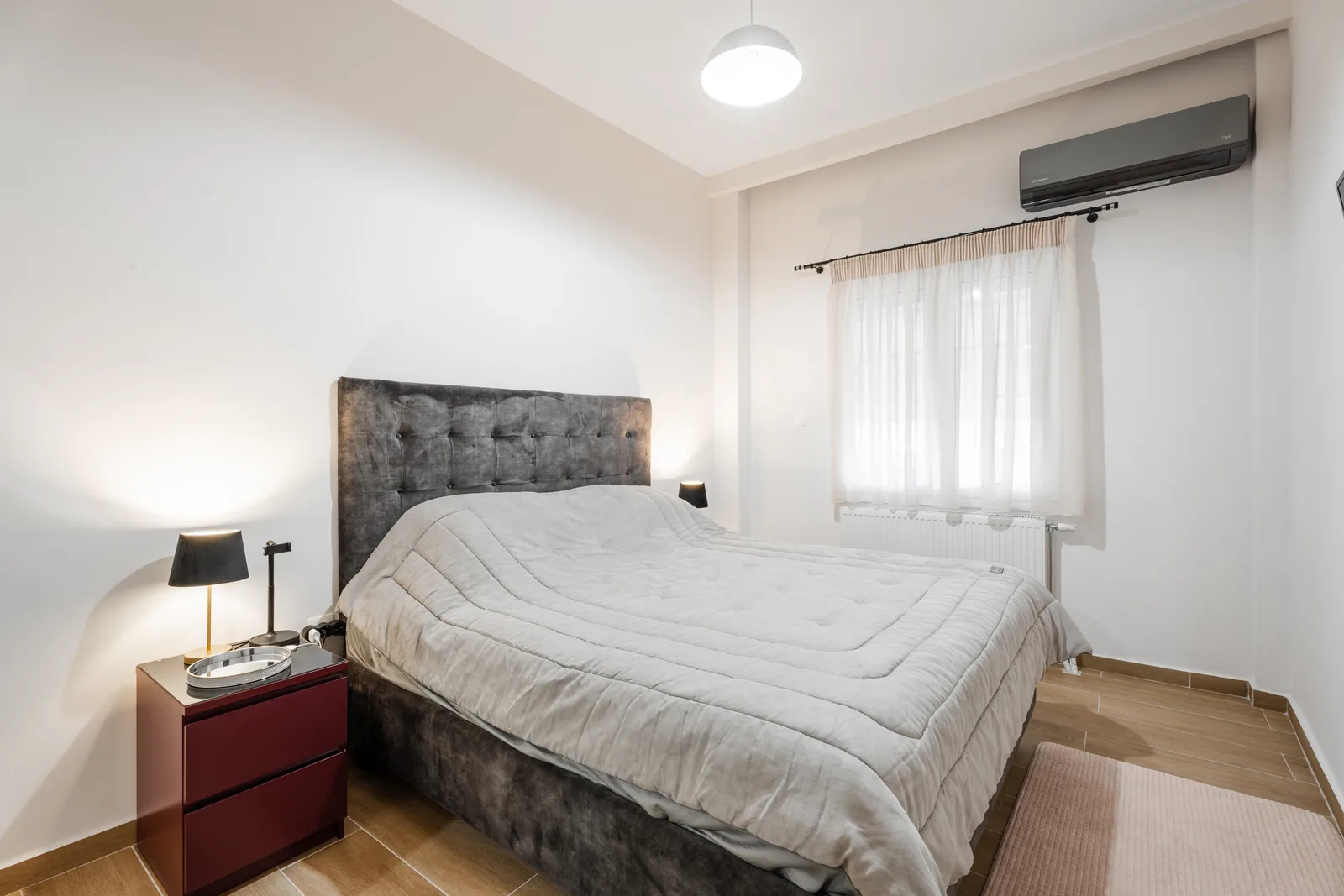 Bedroom with a grey upholstered headboard and a red bedside cabinet